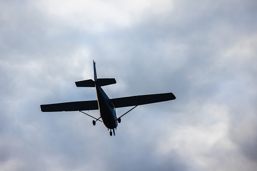Light aircraft silhouette is in cloudy sky on a daytime, close up rear view