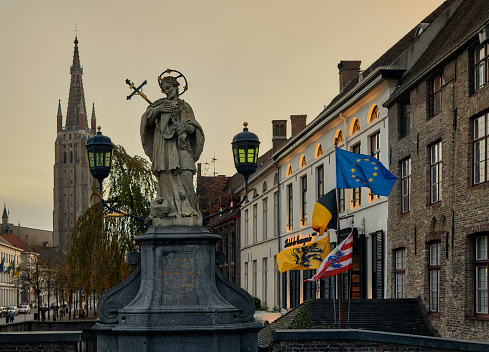 Brujas, Belgium – August 28, 2023: A statue of Saint Joannes Nepomuk on the Wollestraat bridge in Bruges, West Flanders, Belgium