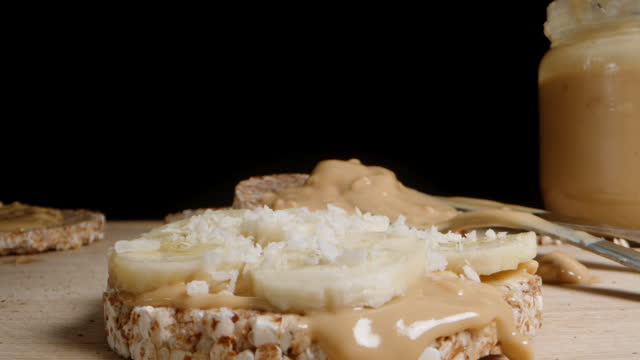 puffed rice bread Sandwich with Peanut Butter and Banana, Sprinkled with Coconut Flakes, a Vegetarian and Healthy Breakfast.