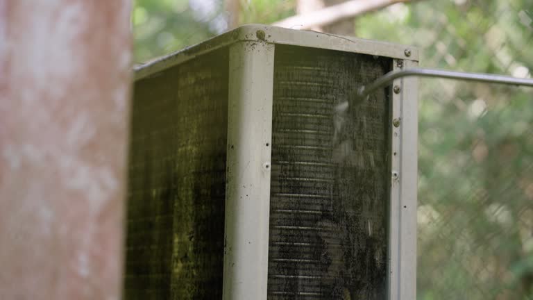 The technician cleans the air conditioner by using water to wash away dust from the hot coil panel.