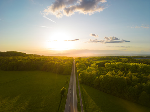 An aerial view of a straight road going through a forest at sunset in Giessen, Hessen, Germany