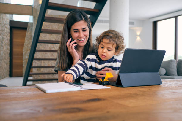 istock Cheerful mother talking on smartphone while sitting with baby 1889480265