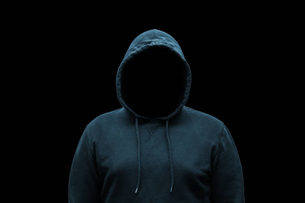 istock Mysterious faceless hooded anonymous criminal, silhouette of computer hacker, cyber terrorist or gangster on black background 1889484274