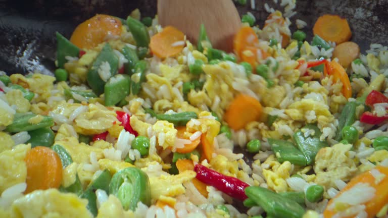 SLO MO Wooden spoon being used to mix the fried rice in the wok