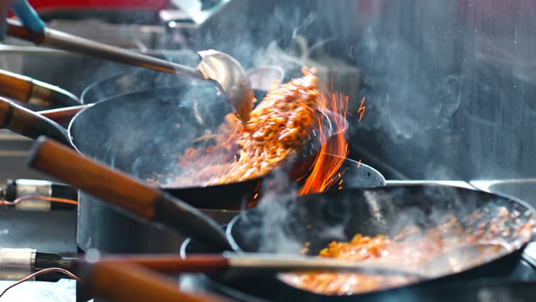 SLO MO Chef in an Asian restaurant tossing the wok before taking it off the gas stove