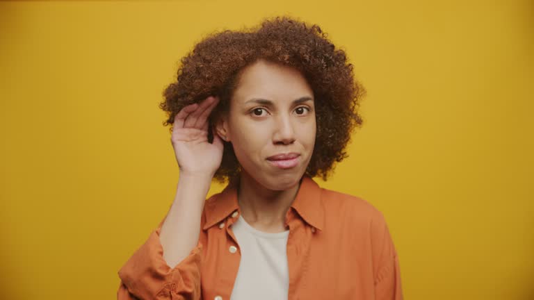 Woman Listen Gesture on Yellow Backgound