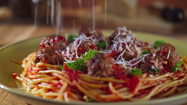 DS Cheese falling onto a plate of spaghetti and meatballs