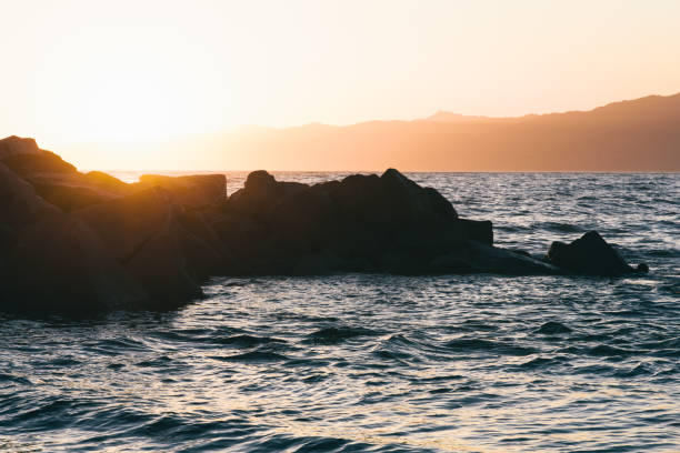 istock Sunset behind the rocks on the beach 1889524462