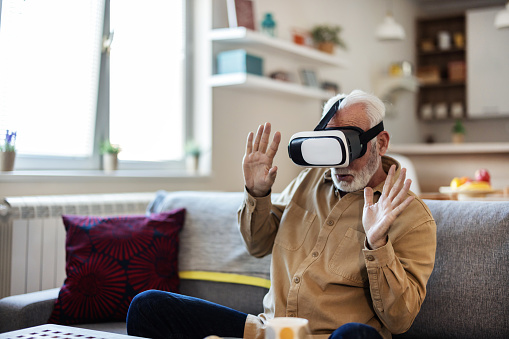 Senior man experiencing virtual reality eyeglasses headset.