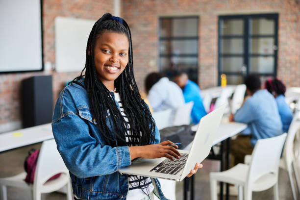 istock Smiling young female college student using a laptop in a classroom 1889543304