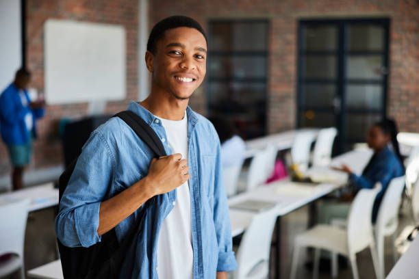 istock Smiling young male college student with a backpack standing in a classroom 1889548864