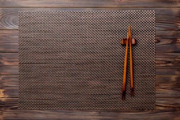 istock Two chopsticks and bamboo mat on wooden background. Top view, copy space 1889558573