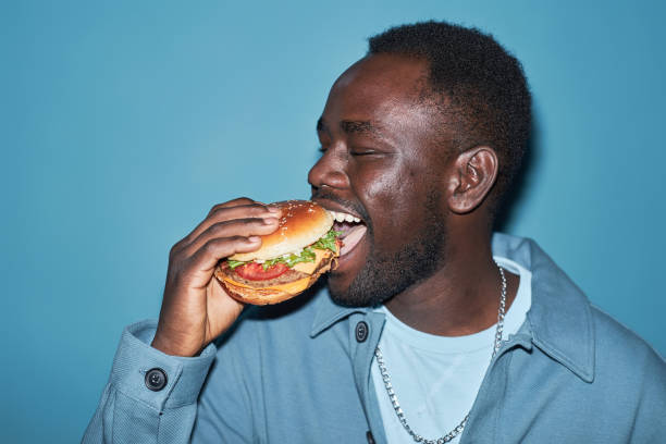 istock Young Hungry Black Man Eating Burger 1889561441