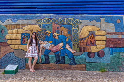 La Boca, Buenos Aires, February 20, 2018: A woman strikes a pose with a mural  at La Boca in the Buenos Aires