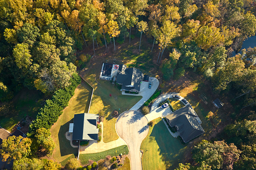 View from above of expensive residential houses between yellow fall trees in suburban area in South Carolina. American dream homes as example of real estate development in US suburbs.