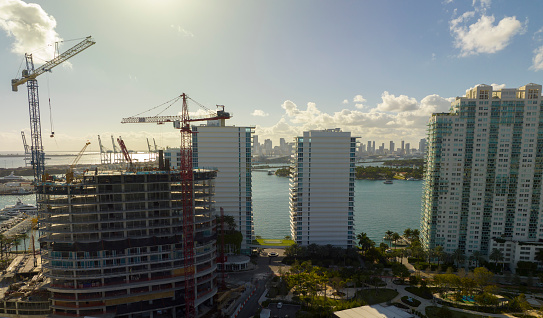 Aerial view of new developing residense in american urban area. Tower cranes at industrial construction site in Miami, Florida. Concept of housing growth in the USA.
