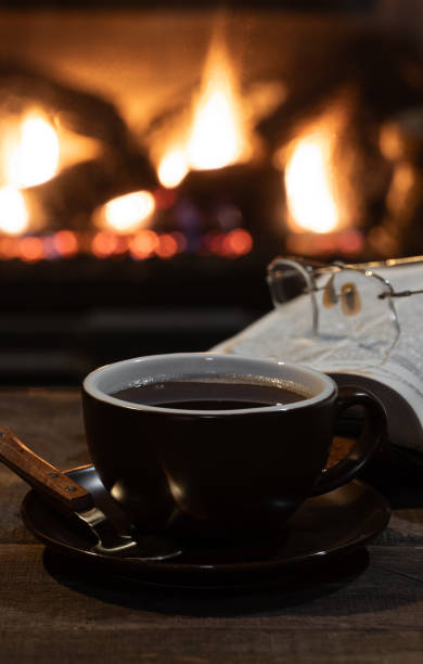 istock Cup of coffee with burning fireplace in background 1889605002