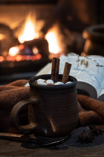 istock Mug of hot chocolate with fireplace burning in background 1889605248