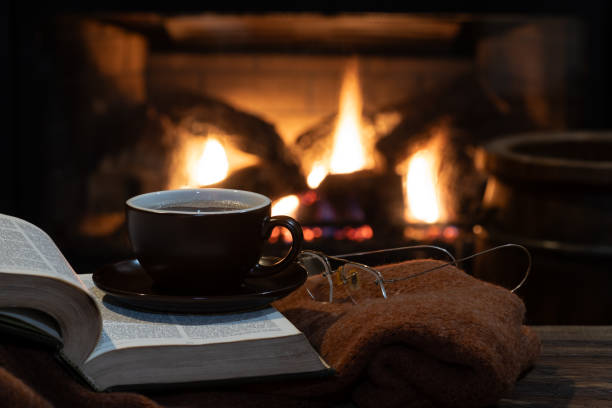 istock Cup of coffee with burning fireplace in background 1889605517