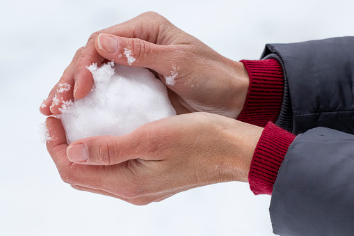 Woman making snowball. Playing active games in winter. Hands holding snowball. Wintertime leisure cold weather.
