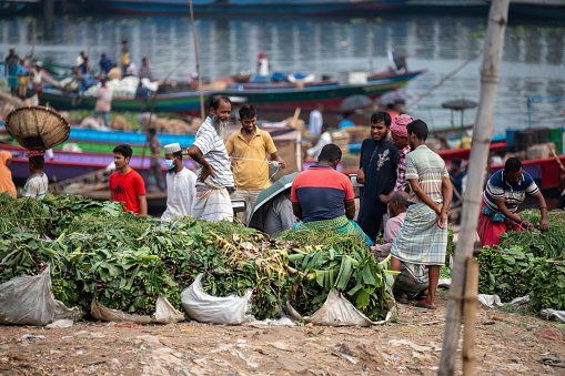 Fruit and vegetable traders on the banks of the Buriganga River in sadarghat region of Dhaka, capital city of Bangladesh. Workers and traders are clearly visible.
