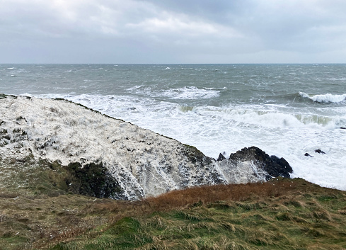 Sea foam casting on to the shoreline - as a storm hits the coastline - creating snow like conditions on the adjoining fields and land
