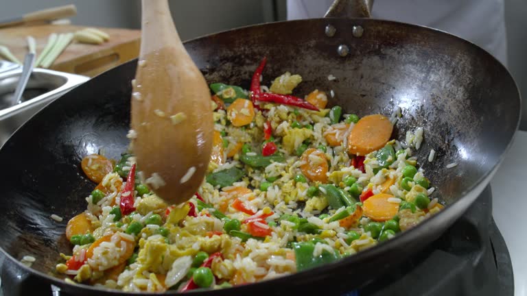 SLO MO Fried rice in the wok being mixed using a wooden spoon