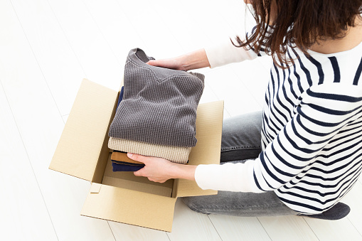 A woman packing clothes into cardboard boxes