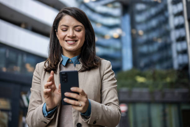 istock Smiling businesswoman reading emails on her mobile phone while on the go 1889696413