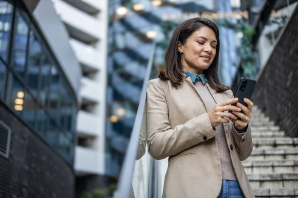istock A business woman uses a mobile phone while on the go 1889696430