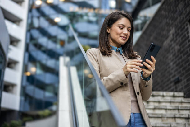 istock Smiling businesswoman reading emails on her mobile phone while on the go 1889696438