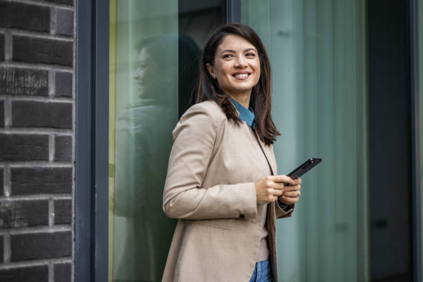 istock Smiling businesswoman reading emails on her mobile phone while on the go 1889696967