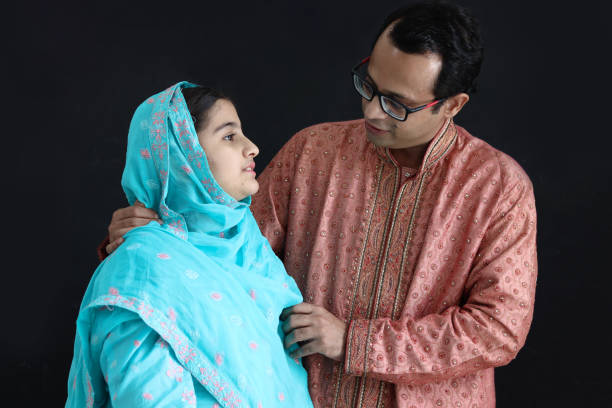 cute indian girl in india traditional blue dress with her father standing on black background, dad hugging daughter kid, looking at each other. portrait of happy indian family, father with child. - men pakistani ethnicity islam malaysian person 뉴스 사진 이미지