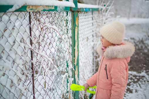 girl stands near a snowy fence