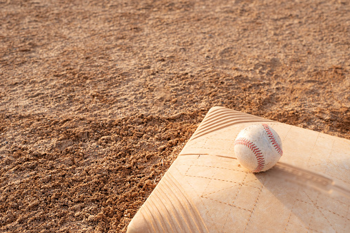 Baseball sitting on a base on a baseball field.