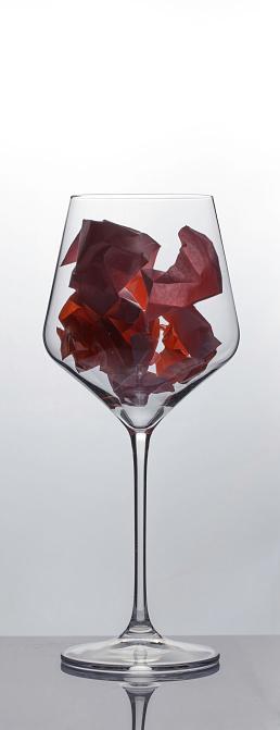 Crumpled adhesive notes in wine glass