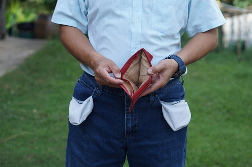 Close up man shows his empty wallet and jeans pockets. Concept, Poor, bad economic crisis. Financial problems. Broke or less money at the end of month. No money.