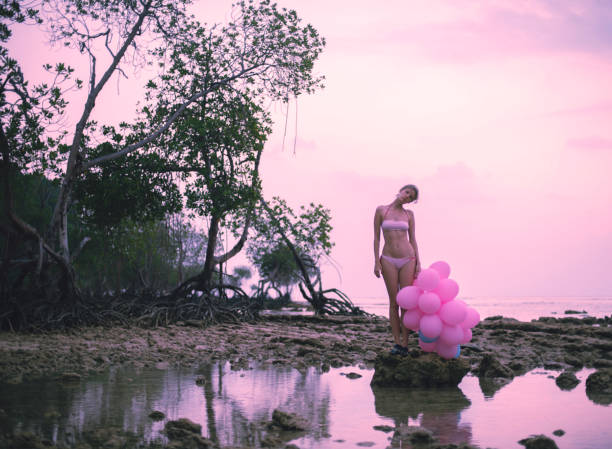 young woman walking with many balloons in sunset at the ocean beach - party beach indian ethnicity adult ストックフォトと画像