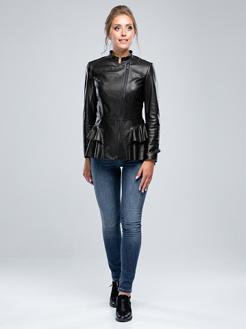 Professional model is posing for lookbook in the studio on white background. Woman wear Leather Jacket and jeans.