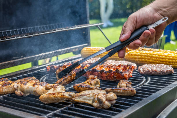 istock Man using tongs to take meat off grill 1889872027