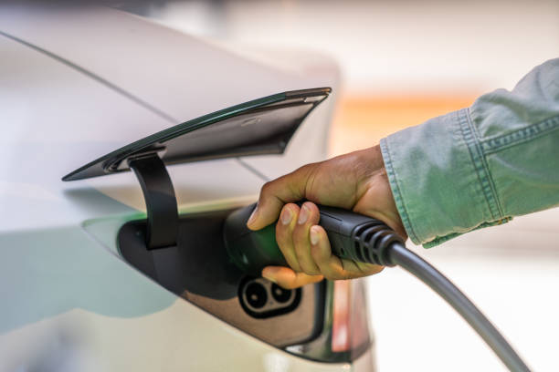 istock Male hand plugging charger into electric car 1889872044