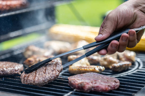 istock Man using tongs to take meat off grill 1889872048