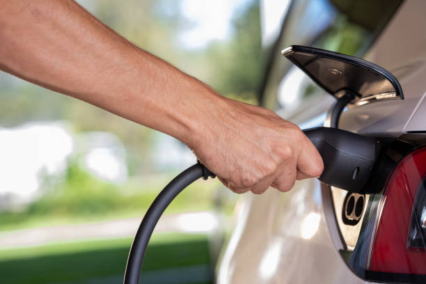istock Male hand plugging charger into electric car 1889872155