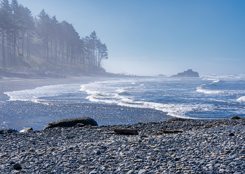 Ruby Beach, WA - USA - Sept. 21, 2021: Horizontal view of visitors admiring the forest edge and waves hitting the rocky shore of Ruby Beach at Olympic National Park.