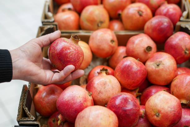 istock A woman chooses pomegranate fruit at a grocery store 1889889328
