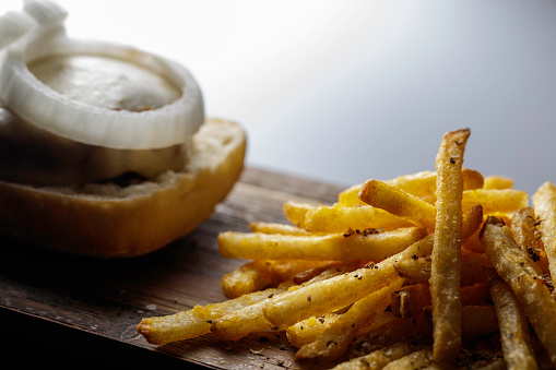 Close up of cheeseburger with raw onion and french fries