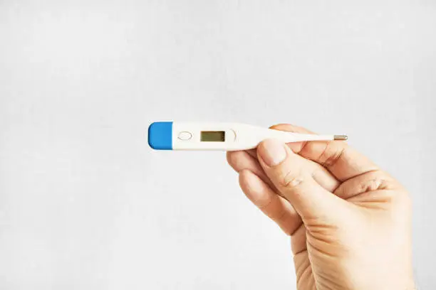 Person hold a Medical Thermometer on the White Wall Background closeup