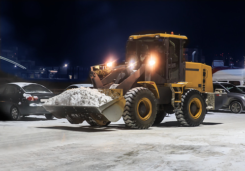 Snow removal with a loader in a parking lot at night