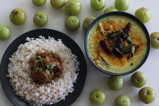 Nellika curry served with Kerala rice meal. Kerala style coconut based Gooseberry curry made of fresh gooseberry, ground coconut and spices. Shot on white background.