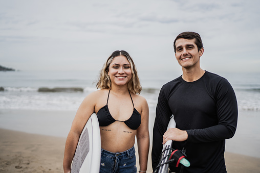 Portrait of a surfer couple holding surfboard on the beach